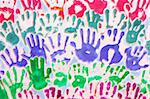 Many hand prints of children in different colors on white background