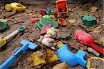 Forgotten toys in a dirty sandbox. Depressive mood.