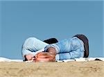 Couple sleeping on the beach with blue sky as a background