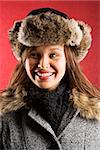 Young adult Caucasian woman wearing fur hat looking to side and smiling.