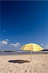 a summer scenic with a yellow umbrella at the beach