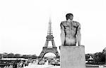 A statue in the foreground with the Eiffel Tower in Paris, France.Black and white. Copy space.