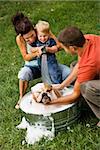 Caucasian Familie mit Kleinkind Sohn geben englische Bulldogge ein Bad im Freien.