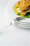 Chicken schnitzel, baked with potato mash, baby spinach and beure blanc sauce. Portrait mid shot with fork on white background