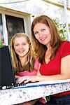 Mother and daughter working on a portable computer at home in the garden