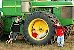 Three Boys Leaning on Large Tractor Wheel