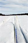 Cross country skiing trail and skis across a frozen lake.