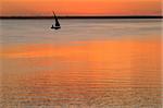 Beach sunset scene in Mozambique with small sailboat (called a dhow)