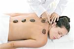 A female receiving massage and hot rock treatment to back and neck at a beauty salon or day spa facility.