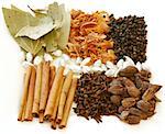 An assortment of fragrant, richly flavored spices - bay leaves, mace, peppercorns, black pepper, silver cardamom pods, cloves and cinnamon.