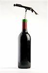 A Bottle of red wine with a corkscrew on a plain background