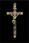 Crucifix religious Christian pendant against black background.