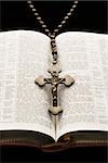 Rosaire avec crucifix sur une Bible ouverte.