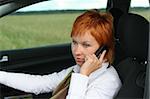 Red-haired woman with mobile-phone in a car
