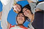 A group of caucasian teens holding onto each other and leaning over looking at the camera while playing in a park