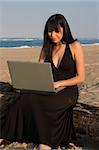 Attractive lady working on a laptop at the beach