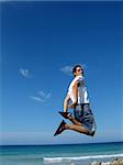 Young boy jumping on air against blue sky