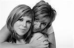 A portrait taken from mother and daughter taken on a white background holding on to each other