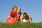 Woman and kids playing in the grass on a beautiful autumn afternoon with large rubber balls