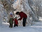 Happy family (mother with small boy and girl) in winter snow covered city park