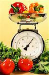 Fresh veggies on kitchen scale with yellow background