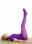 A very fit seventy year old woman performing the double leg raise position in yoga. White background