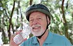 A senior man taking a water break after riding his bike.