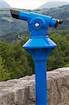 Modern coin telescope on focus over landscape blurred