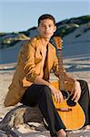 Young man with his guitar at the beach
