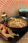 A steaming bowl of hot & sour soup and golden fried fantail shrimp served at a Chinese restaurant.