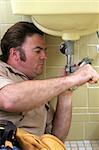 A plumber using a pipe wrench to tighten a pipe.