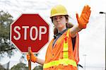 A female construction worker holding a stop sign.