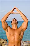 Young Man Meditating Near Ocean with Hand up in the Air