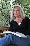 A beautiful, mature woman reading an inspirational book on her porch swing.