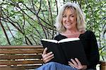 A beautiful woman taking time out of her day to read a book and relax.