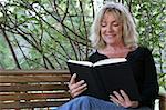 A beautiful woman enjoying a good book on her porch swing.