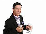 A handsome man in a tuxedo with a champagne bottle and two glasses.