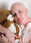 A medical patient hugging a teddy bear and looking afraid.