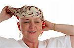A beautiful woman, bald from chemotherapy,  prepares to remove the scarf covering her head.  Second in a sequence.