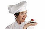 A friendly female chef holding a strawberry cheesecake tart.  Isolated on white.