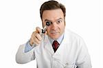 Closeup of a doctor peering into an otoscope directly toward the camera.
