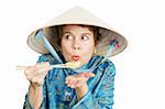 A tourist dressed in chinese clothing blowing on a fried dumpling to cool it.  Isolated on white.