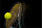 Tennis racket and ball on black background