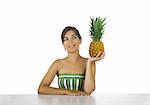 Beautiful young woman in the kitchen looking to a pineapple