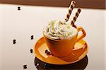 cup of coffee with whipping cream and chocolate sticks