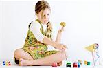 Studio portrait of a young blond girl who is playing with paint and eggs for easter