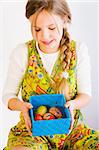 Studio portrait of a young blond girl who is shwong a box full of easter eggs