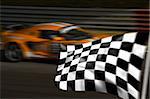 Orange racing car passing the chequered flag with motion blur
