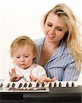 Portrait of an attractive young mother and an adorable blond toddler in front of a portable keyboard