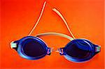 Pair of blue swimming goggles on an orange background